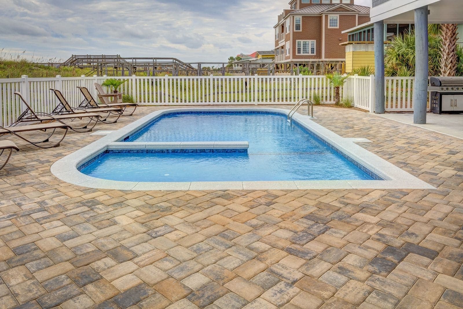 In-ground pool and attached spa with a wide paver deck